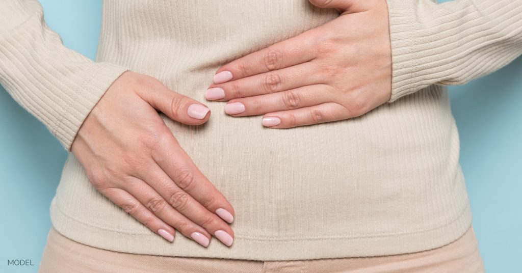 woman holding her stomach with both hands (model)